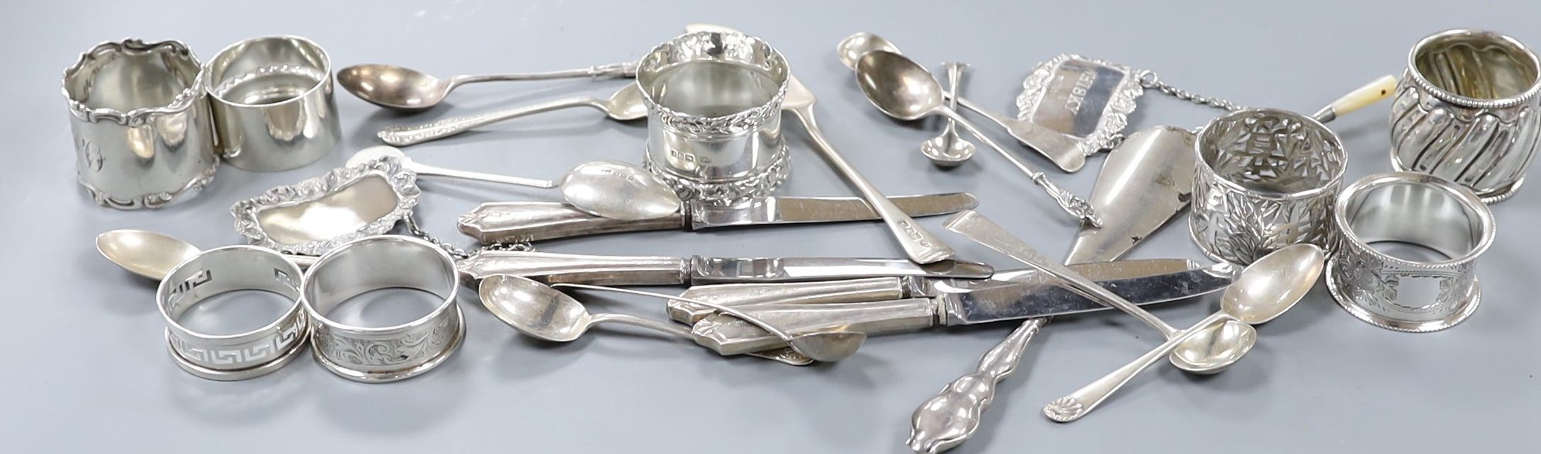 A quantity of small silver cutlery, a pair of silver decanter labels, Sherry and Whisky and eight various silver serviette rings.